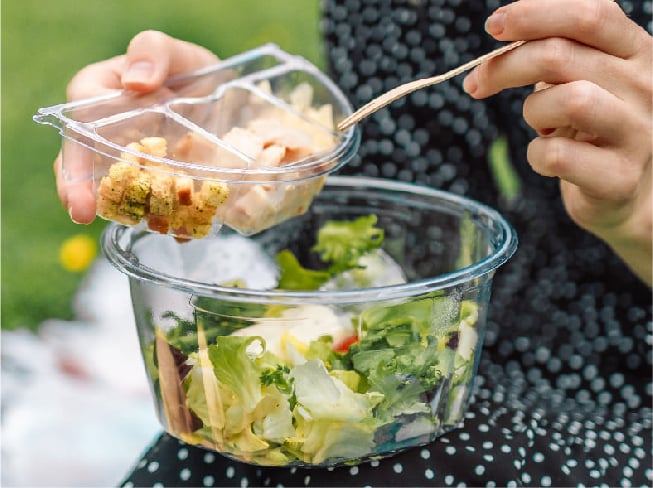 person-eating-salad-in-plastic-container